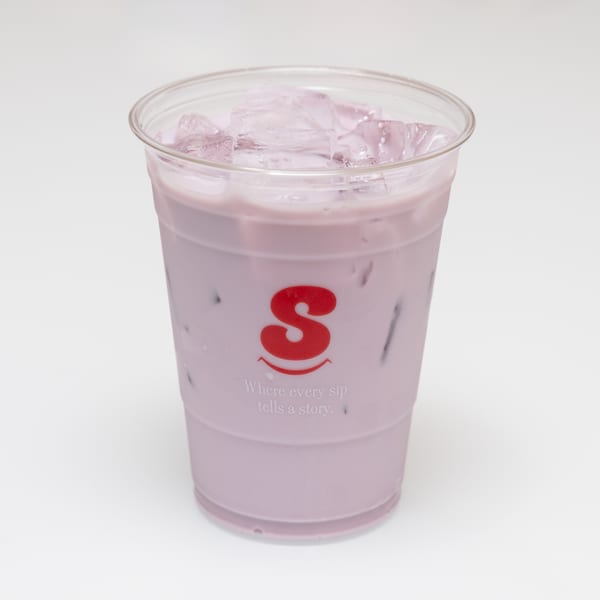 A plastic cup of iced purple taro milk tea with a red "S" logo and text.