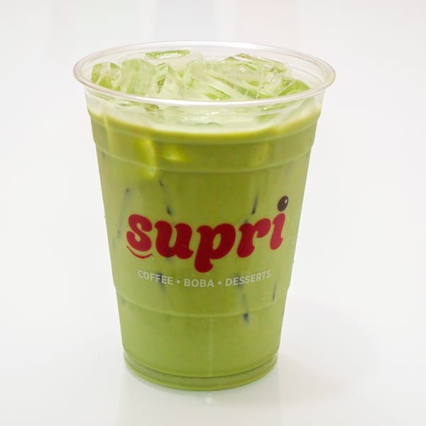 Iced matcha latte with boba pearls in a clear plastic cup with the Supri logo.