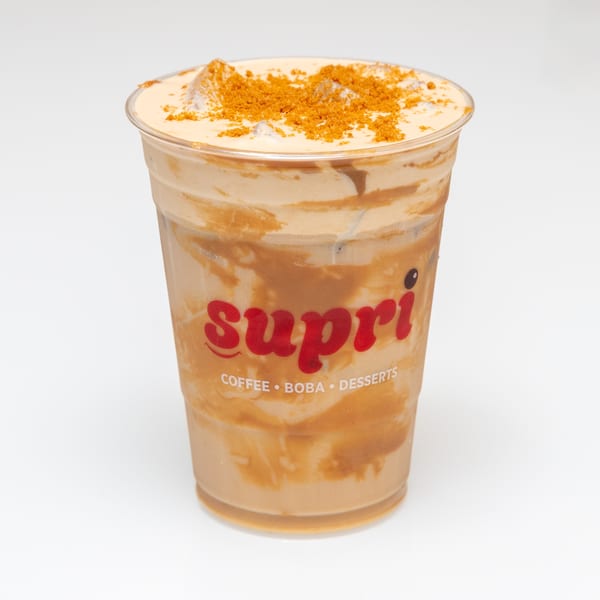 A Supri brand iced coffee drink with a creamy top layer and cookie crumbles.